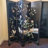 A black painted oriental four panelled fire screen decorated with red headed cranes and roses.