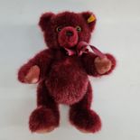 A Steiff 012983 burgundy teddy bear wearing bow. Important: Online viewing and bidding only. No in
