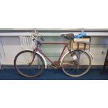 Pilgrims maroon painted bicycle with basket to front.