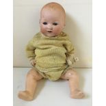 An A.M. Germany 651.8.K. porcelain faced doll with composite body snuffers wool outfit with cap.