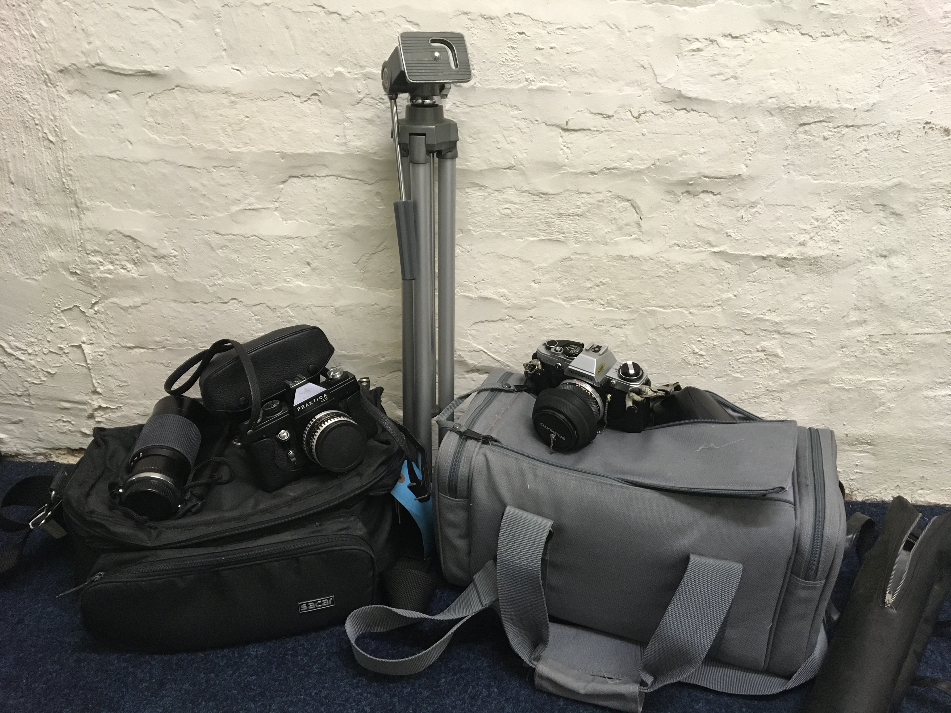 A selection of camera equipment to include Praktica LLC camera, Ozeck lens, tripod, Olympus OM10