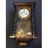 A wall hanging clock with Roman numerals to face and twisted columns to sides, approx height 66cm.