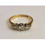 A hallmarked 18ct yellow gold three stone diamond ring, illusion set with a central round