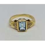 An 18ct yellow gold aquamarine and diamond ring, the central emerald cut aquamarine measuring