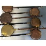 Eight various copper and brass warming pans with wooden handles, together with a copper coaching