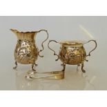 A hallmarked silver milk jug and sugar bowl with sugar tongs, milk jug and sugar bowl having