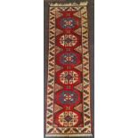 An Afghan runner with six medallion pattern on red background, 300cm x 71cm. IMPORTANT: Online