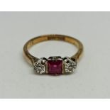 A ruby and diamond three stone ring, set with a central square cut ruby (possibly synthetic) flanked