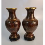 A pair of cloisonné vases with floral design and gold rims, on wooden bases, height 27cm. IMPORTANT: