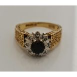 A hallmarked 18ct yellow gold sapphire and diamond cluster ring with patterned shoulders, ring size