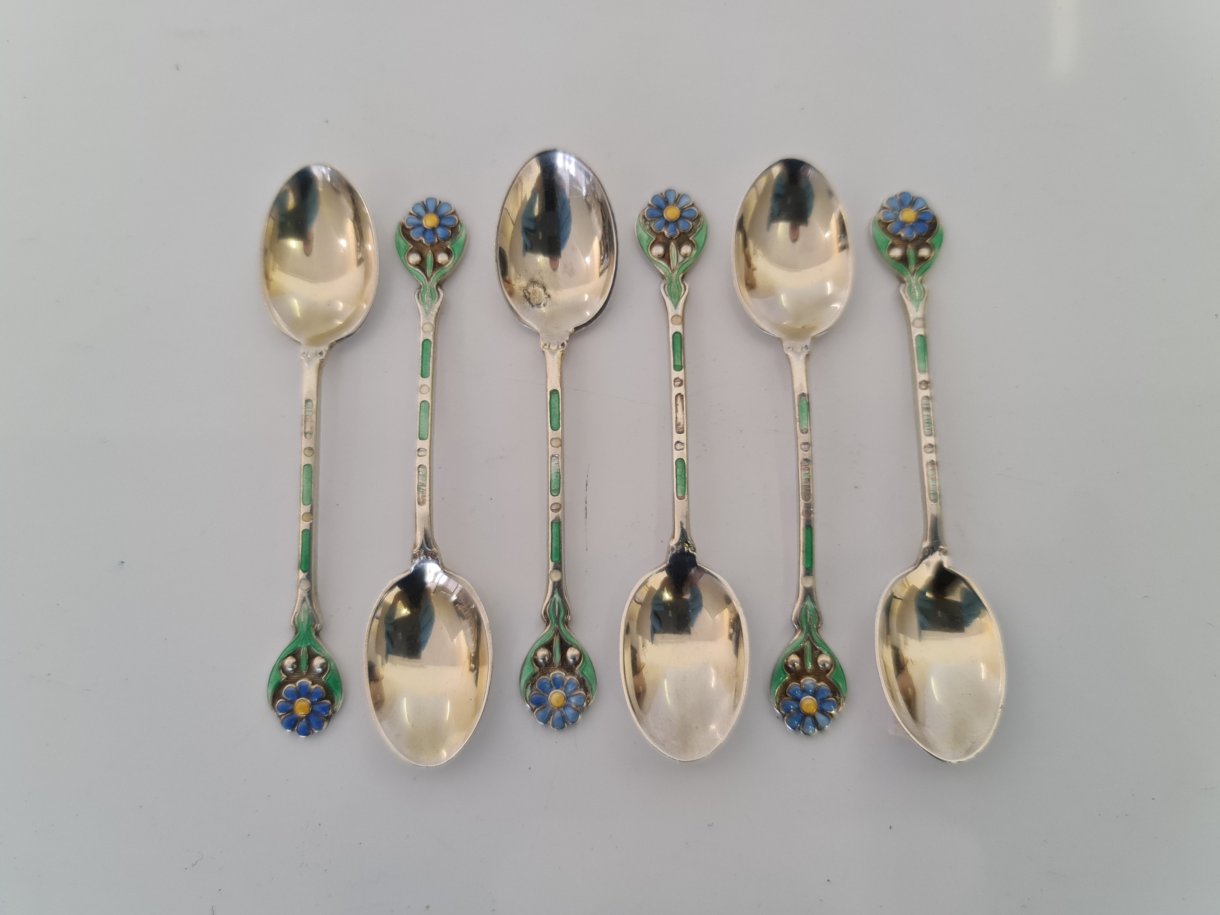 A set of six hallmarked silver and enamel spoons with flower design on handle, approx. weight 53.