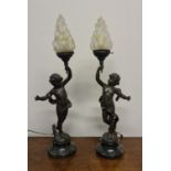 A pair of Moreau spelter table lamps in the form of boys, on marble base, with frosted glass flame