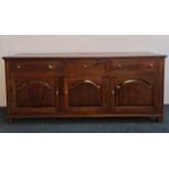 A Wakeman oak reproduction 18th century style dresser base with three drawers and three doors.