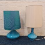 Two mid-century blue glass based table lamps, one with turquoise shade and one with cream.