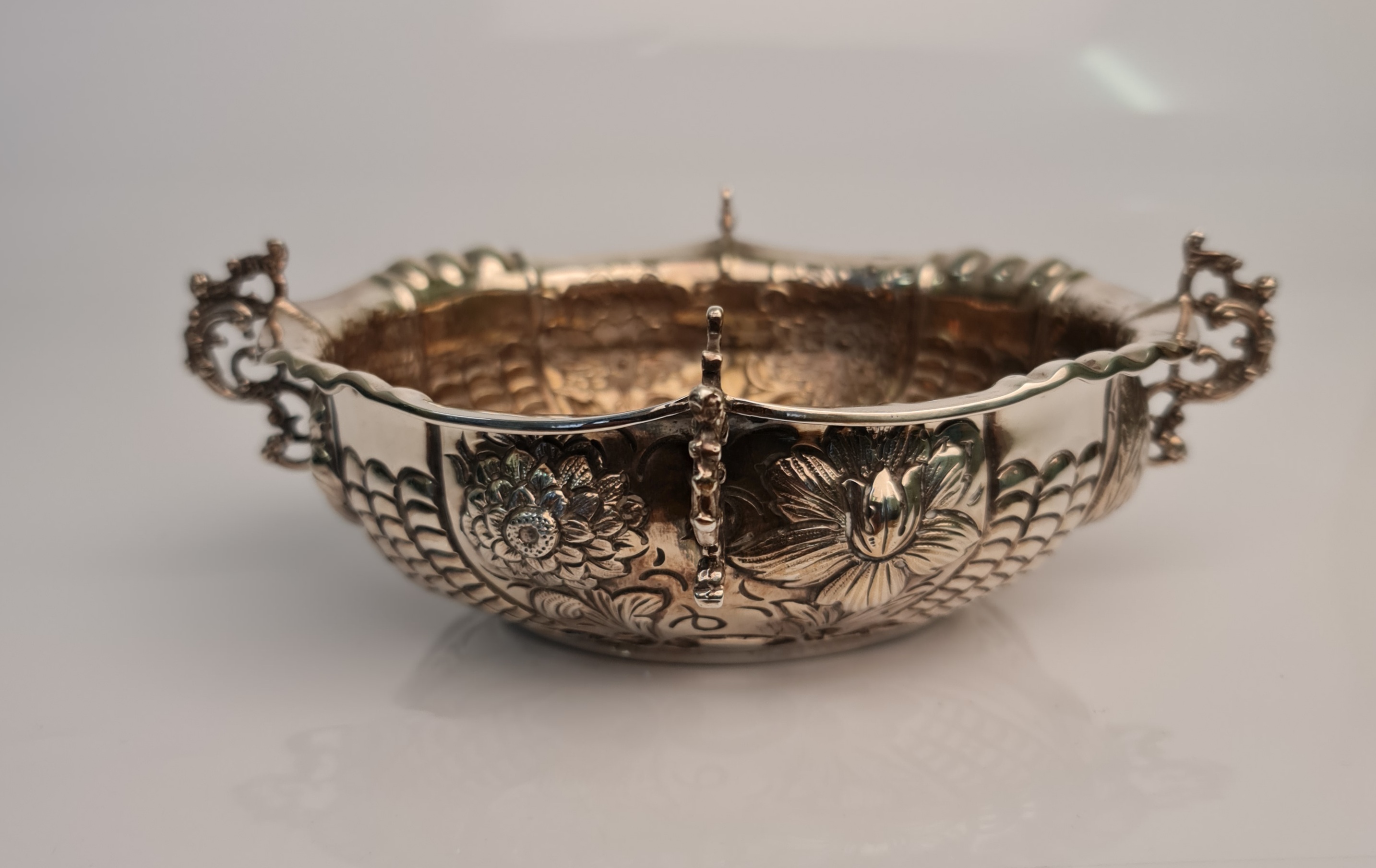 A Victorian silver dish, of oval form with repousse floral desing and four scrolling handles,