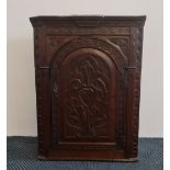 A late 18th century oak carved front wall mounted single door corner cupboard, height 92.5cm.