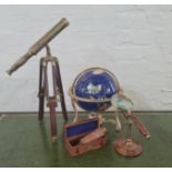 A small telescope, a small gemstone style terrestrial globe, a magnifying glass in stand and a