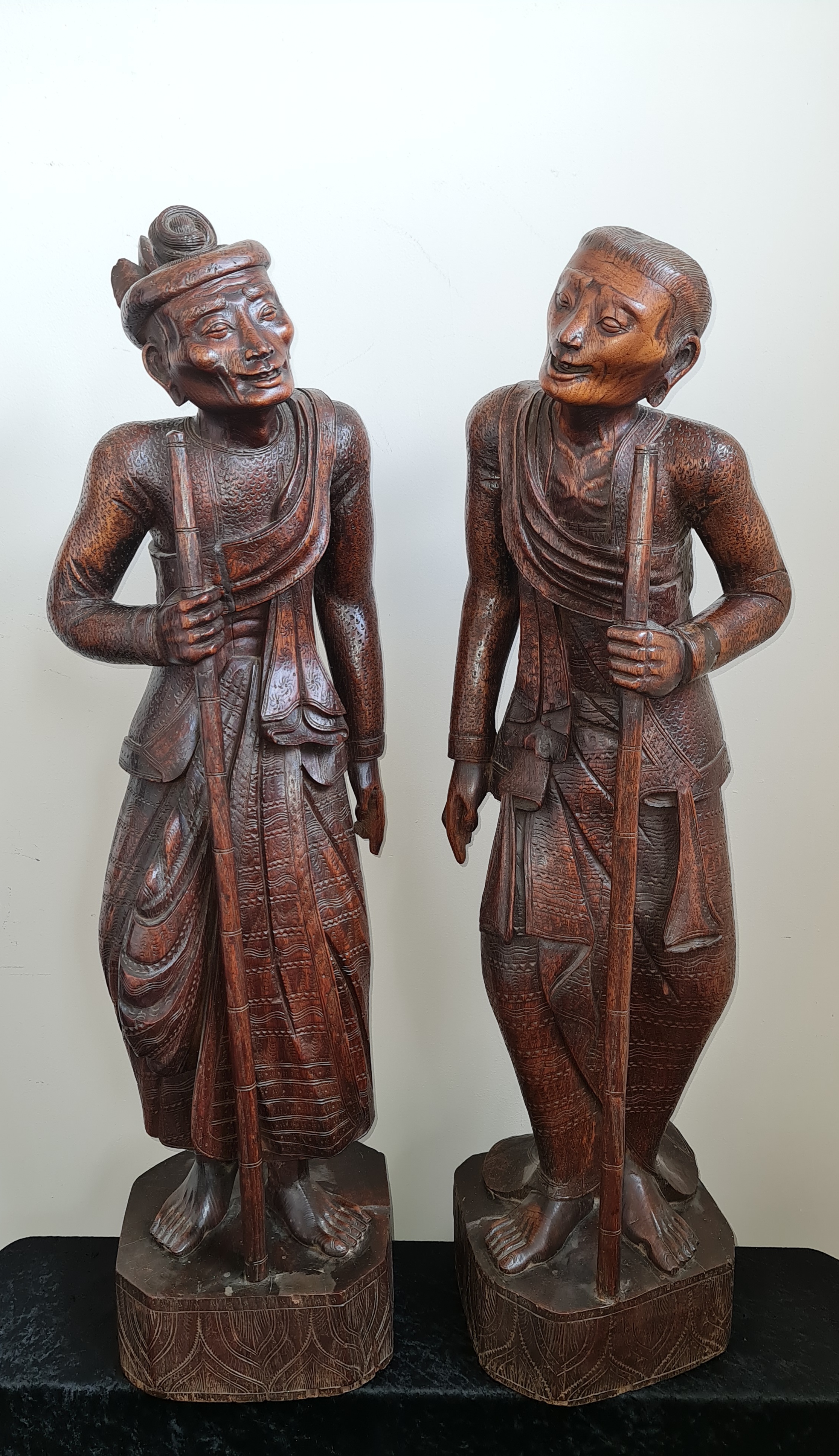 Two 19th century large oriental one piece carved wood male and female elderly traveller figures,