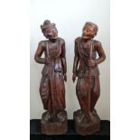 Two 19th century large oriental one piece carved wood male and female elderly traveller figures,