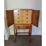 An Art Deco style walnut two door miniature cabinet on drawer base on four square tapering legs with