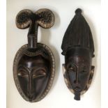 Two West African tribal face masks, with diamond borders and traces of white painted detail.