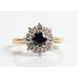 A hallmarked 18ct yellow gold (rubbed) sapphire and diamond cluster ring, set with a central round