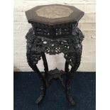 A late 19th century carved hardwood Chinese marble top plant stand with intricate carvings to legs