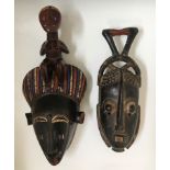 Two West African tribal face masks, one blue and red painted details topped with female, one