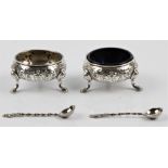 A pair of Victorian silver salts, having repousse floral design to body and raised on three hoof
