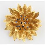 A hallmarked 18ct yellow gold sapphire flower brooch, the flower design set centrally with round cut