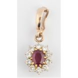 A ruby and diamond cluster pendant, centrally set with an oval cut ruby, measuring approx. 6x5mm,