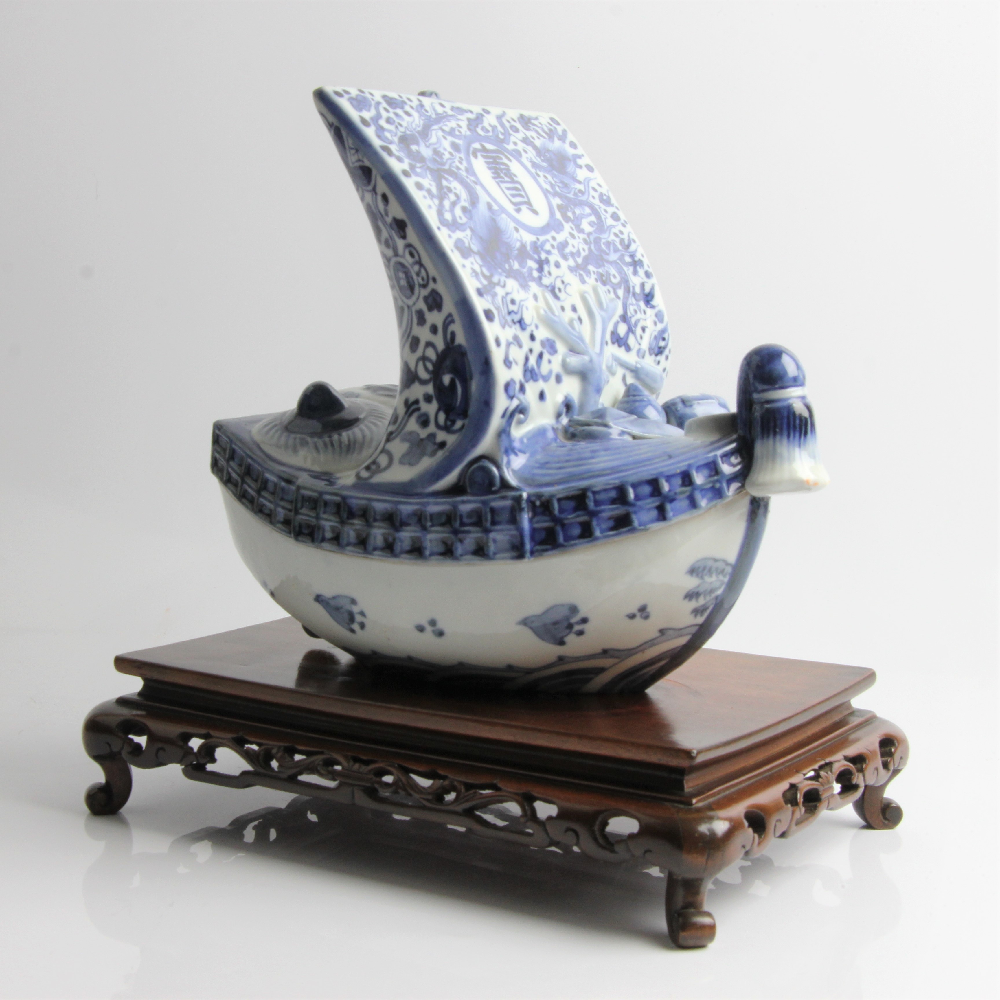 A Chinese blue and white ceramic sailing ship in two parts, decorated with dragons and character