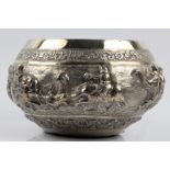 A Burmese white metal bowl, featuring repousse lion hunt scenes and floral design borders, stamped