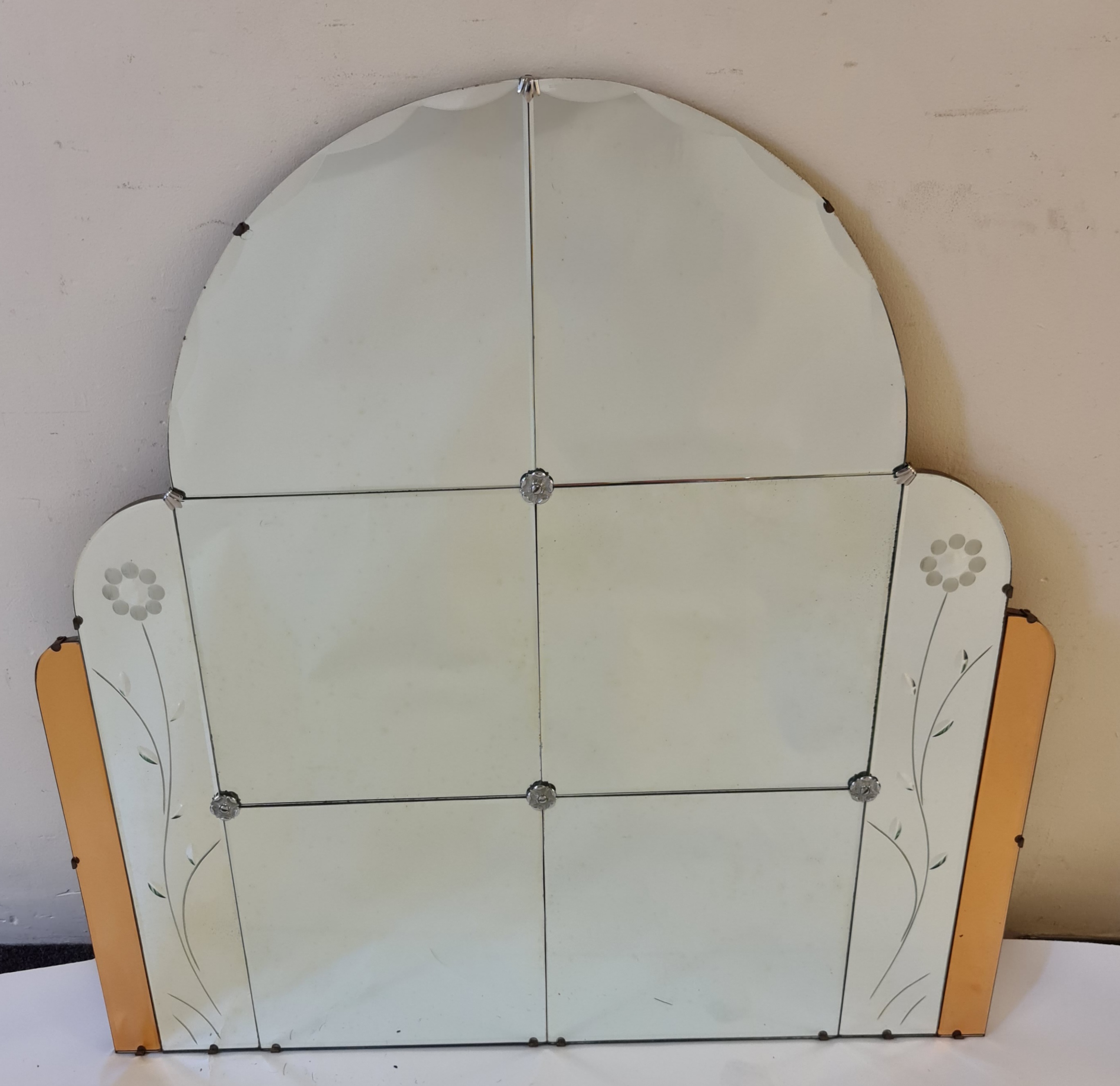 An Art Deco style multi glass panel arch shaped mirror with amber glass and floral motif to sides,