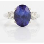 A tanzanite and diamond three stone ring, set with a central oval cut tanzanite, measuring approx.