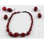 A string of cherry Bakelite beads, comprising 21 graduated oval beads, separated by black faceted