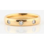 A hallmarked 18ct yellow gold diamond set wedding band, set with three round brilliant cut diamonds,