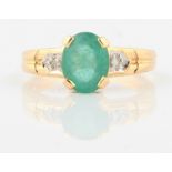 A hallmarked 18ct yellow gold emerald and diamond dress ring, set with a central oval cut emerald