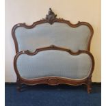 A 19th century French walnut carved bed frame, blue padded upholstery to top and foot board.