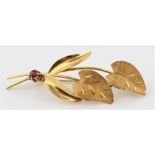 A leaf design brooch, set with a round cut ruby accent, stamped 18ct 750. BOOK A VIEWING TIME SLOT