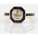 A diamond and sapphire dress ring, set with a central emerald step cut diamond, measuring approx.