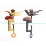 Two hemming bird clamps, each with rectangular frame below a pin cushion and a sprung bird with