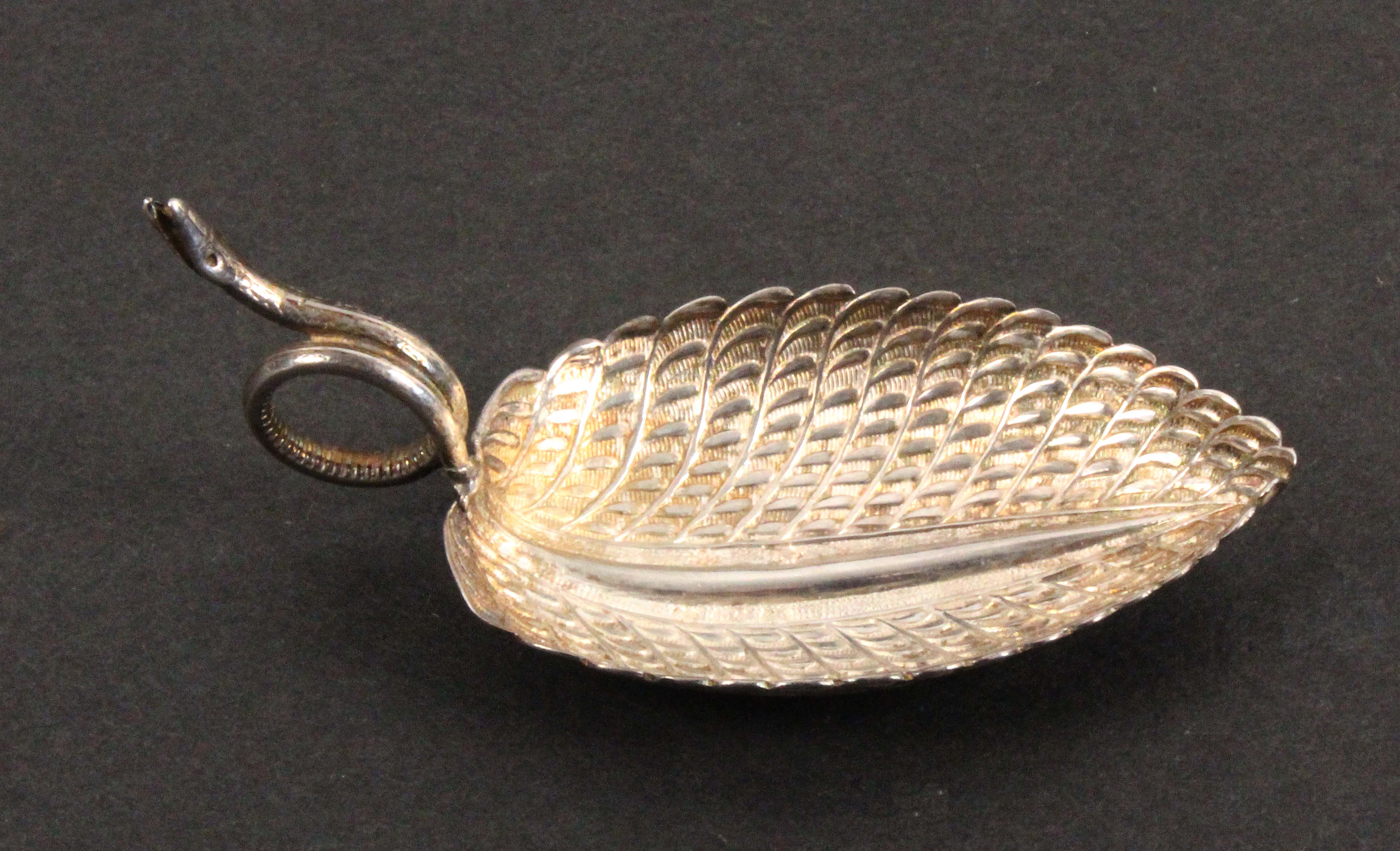 A silver caddy spoon, the leaf shaped and decorated bowl with the handle formed as an encircled