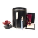 Asprey - London, desk accessories, comprising a black leather cylinder waste paper bin, gilt