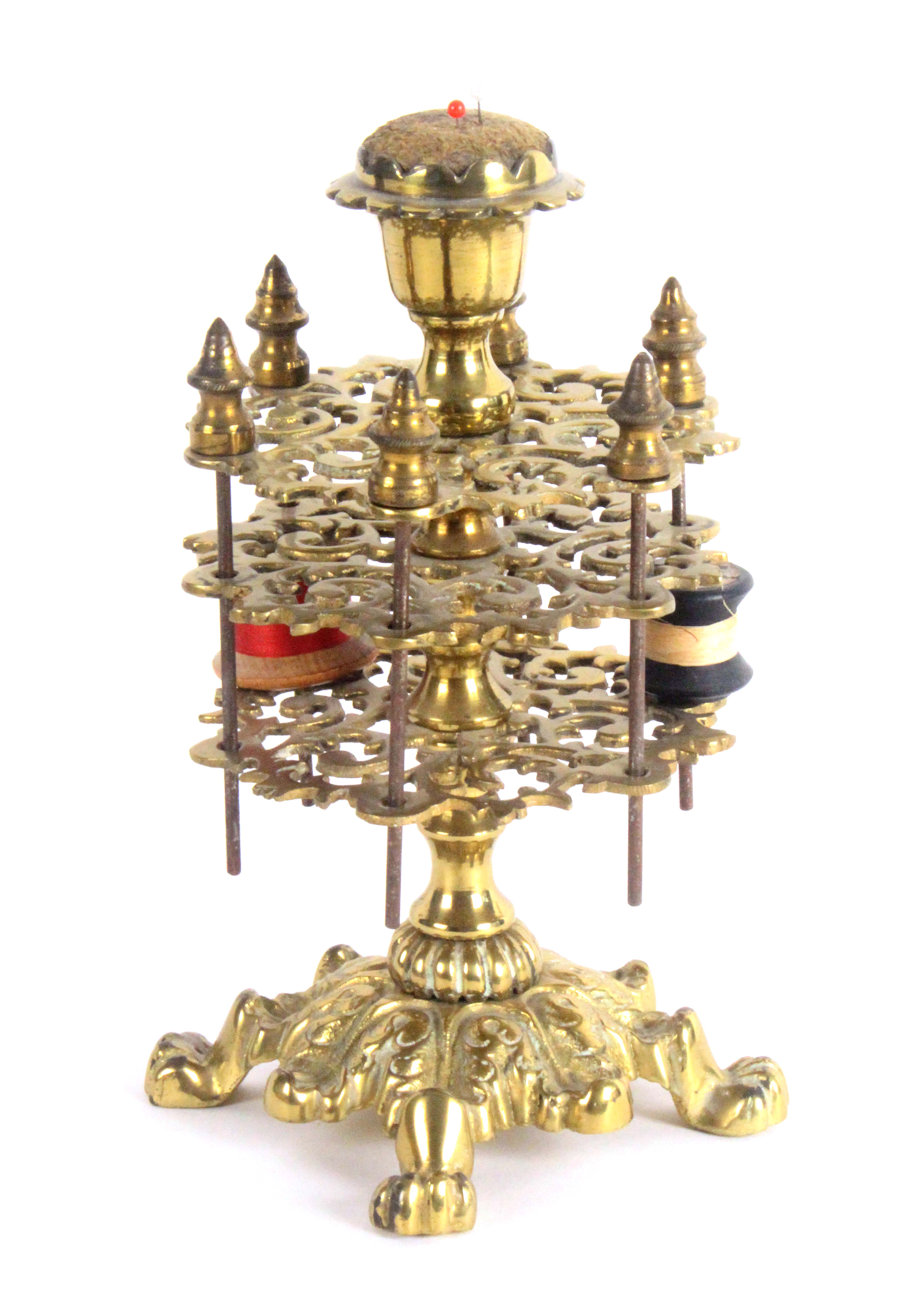 A gilt brass reel stand, circa 1860, the leaf cast base on four lion paw feet, the baluster stem