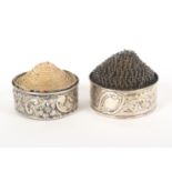 Two silver 'Pyramid pin cushion' holders, of circular form with scroll and floral decoration, one