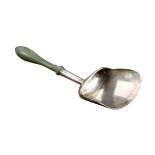 A silver caddy spoon, the shovel form bowl on turned tapering handle terminating in a green