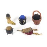 Five pin cushions, comprising a gilt brass example in the form of a set of bellows, 11.5cms, a