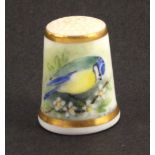 A Royal Worcester black mark thimble, painted with a blue tit on a flowering branch and a further