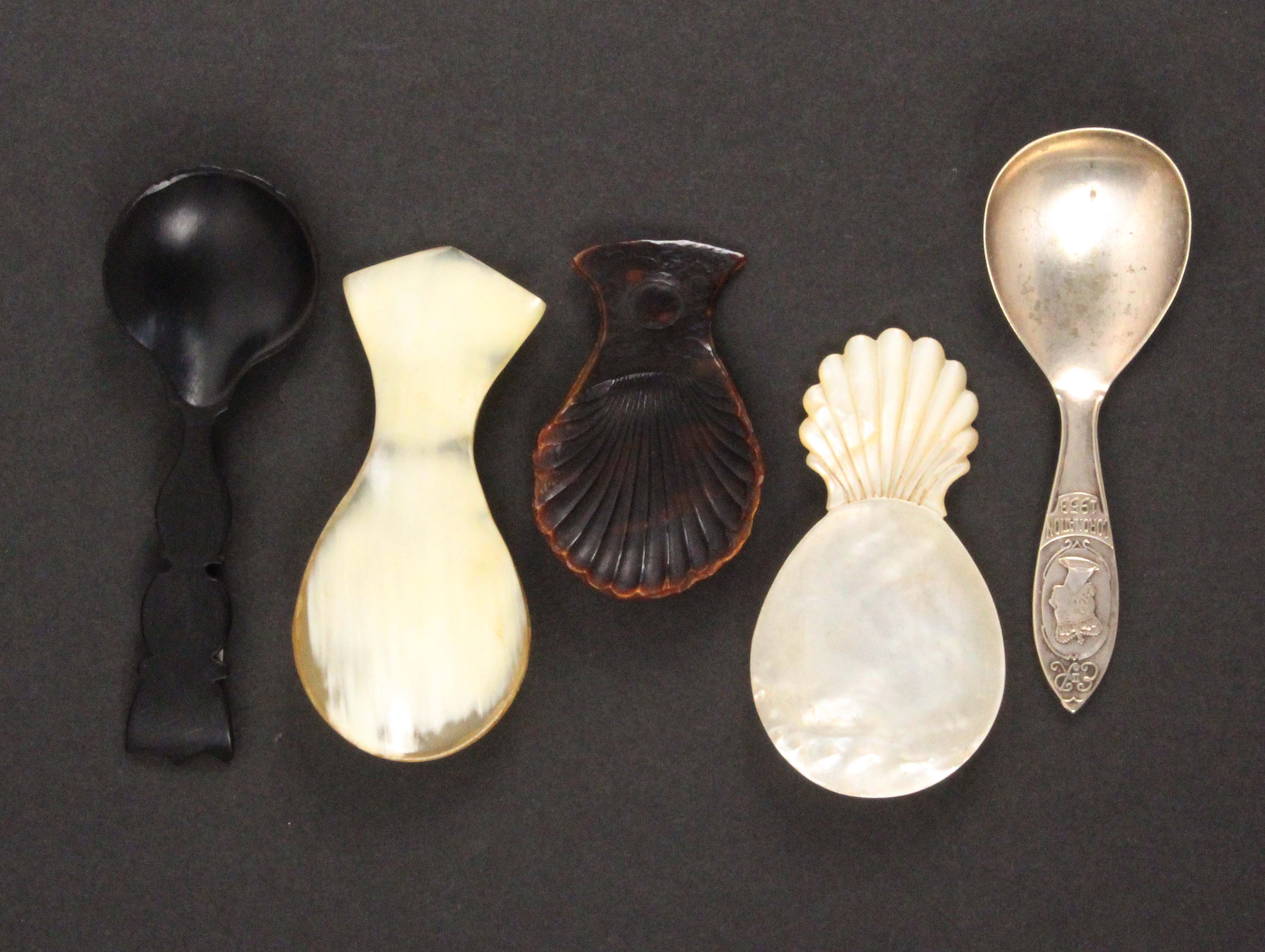 Five caddy spoons, comprising a mother of pearl example with carved handle, 7.5cms, a pressed